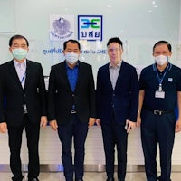 four men wearing face masks standing in front of a building