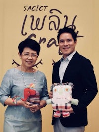 a man and a woman holding stuffed animals in front of a sign