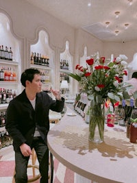 a man sitting at a bar with a vase of roses