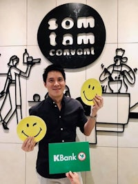 two men holding up smiley faces in front of a bank