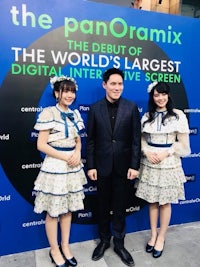 three women posing in front of the world's largest digital interactive screen