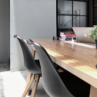a wooden table with black chairs and a laptop on it