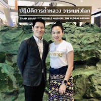 a man and woman posing for a photo in front of a sign