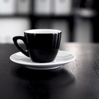 a black and white coffee cup sits on a wooden table