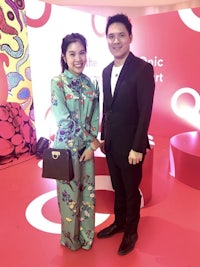 a man and woman posing for a photo in front of a red wall