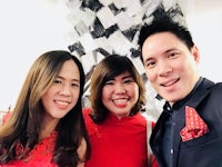 three people posing for a photo in a red dress