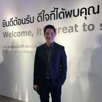 a man in a suit standing in front of a welcome sign