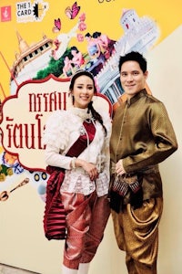 two people posing in front of a poster of thailand