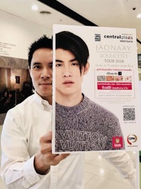 a man holding up a poster in a mall