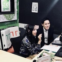 two people sitting at a table in front of a microphone