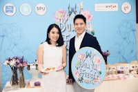 a man and woman standing in front of a table with food