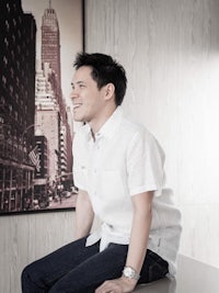 a man in a white shirt sitting on a table in front of a picture